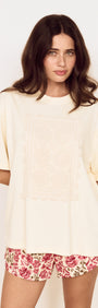 Model wearing a Crochet Detail Oversized T Shirt in soft cream with a crochet applique panel and scalloped edging.