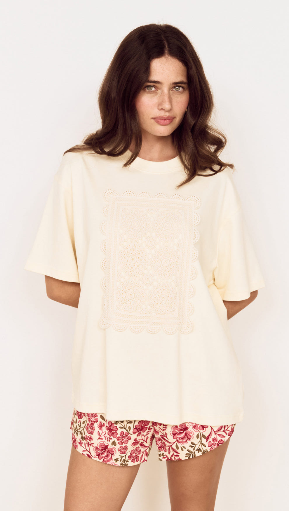 Model wearing a Crochet Detail Oversized T Shirt in soft cream with a crochet applique panel and scalloped edging.