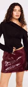 Model wearing a stylish Purple Sequin Mini Skirt paired with a black top, showcasing modern party fashion.