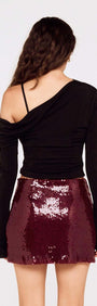Model wearing a fitted black top with the Purple Sequin Mini Skirt, showcasing its sparkling deep burgundy sequins.
