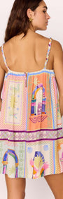 Back view of a model wearing a multicolour print Babydoll Mini Dress, showcasing its vibrant patterns and straps.