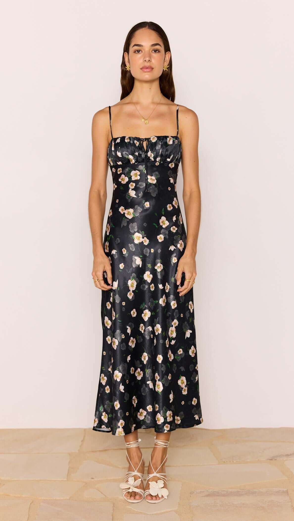 Model wearing a Black Floral Bias Midi Dress with adjustable straps and ruched bust showcasing a floral satin fabric.