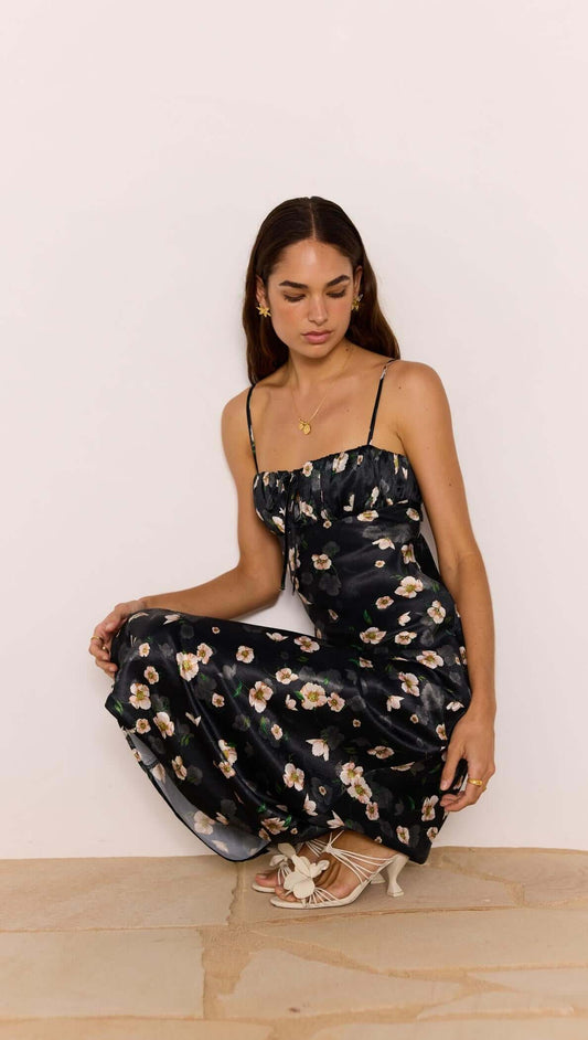 Black Floral Bias Midi Dress worn by model, featuring a ruched bust and keyhole tie detail, perfect for special occasions.