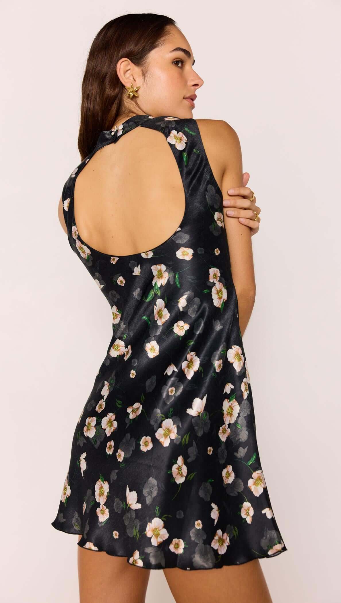 Woman wearing Black Floral Bias Mini Dress showcasing open back design and floral satin fabric.