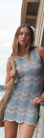 Model wearing a Blue & Cream Knit Mini Dress with a scalloped hem, by the waterfront.