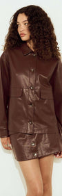 Model wearing a Brown Faux Leather Jacket styled with a matching skirt, showcasing a relaxed silhouette and button-front design.