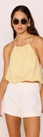 Butter Yellow Halter-Neck Low Back Bubble Top styled with white shorts, perfect for summer outfits.