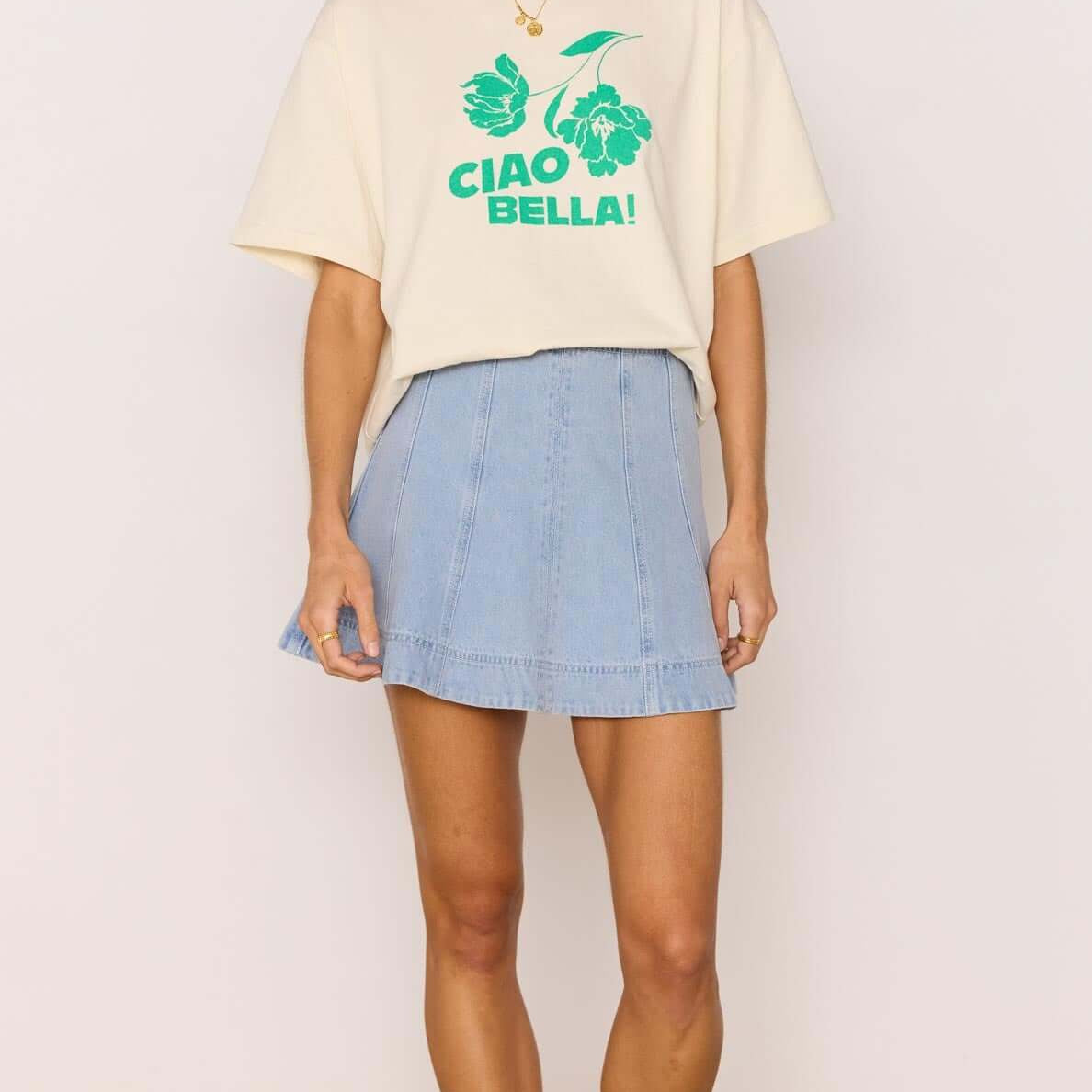 Model wearing a denim flared mini skirt with a graphic tee, showcasing a stylish summer outfit.