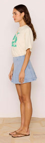 Side view of a model wearing a Denim Flared Mini Skirt with a casual tee and flip-flops.