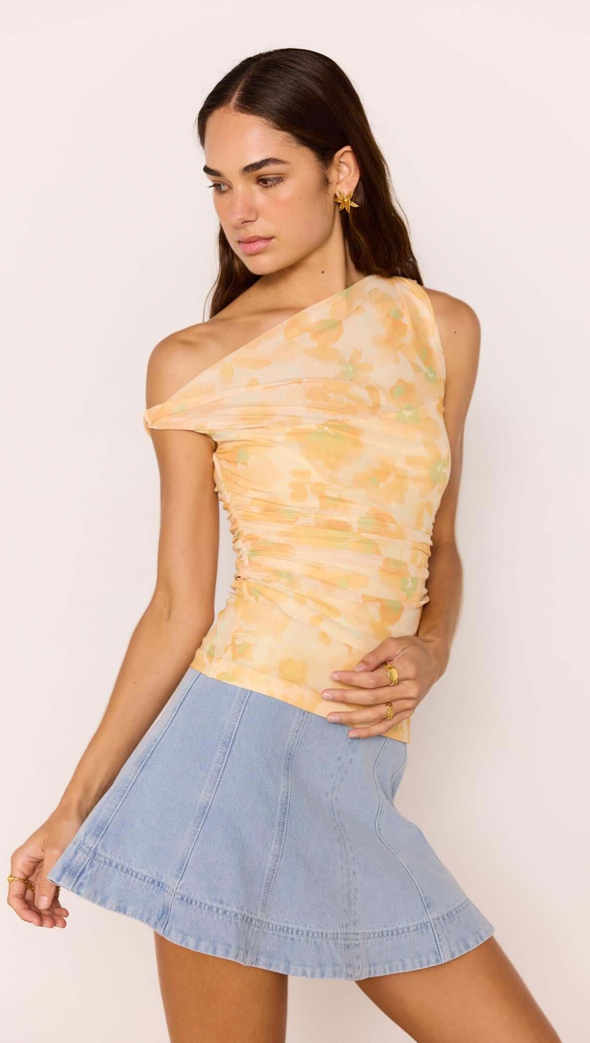 Model wearing a soft yellow one-shoulder top with a Denim Flared Mini Skirt, showcasing a playful and stylish outfit.