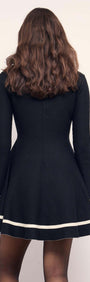 Black Peplum Knit Mini Dress With Contract Trim displayed from the back, featuring flared cuffs and modern trim.