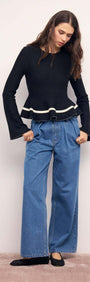 Model wearing a Black Peplum Knit Top With Contrast Trim paired with wide-leg jeans.