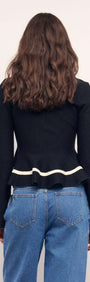 Back view of a model wearing a Black Peplum Knit Top With Contrast Trim and high-waisted jeans.