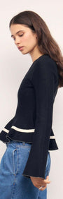Black Peplum Knit Top With Contrast Trim worn by a model, showcasing the playful peplum hem and contrast trim.