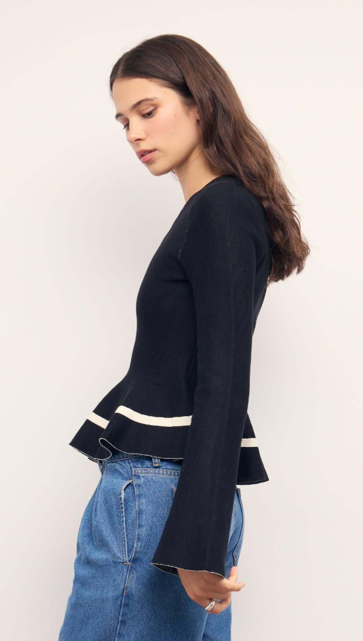 Black Peplum Knit Top With Contrast Trim worn by a model, showcasing the playful peplum hem and contrast trim.