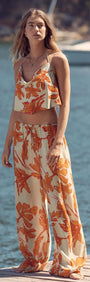 Woman wearing Green & Orange Floral Drawstring Wide Leg Pant by the water, showcasing a stylish summer look.