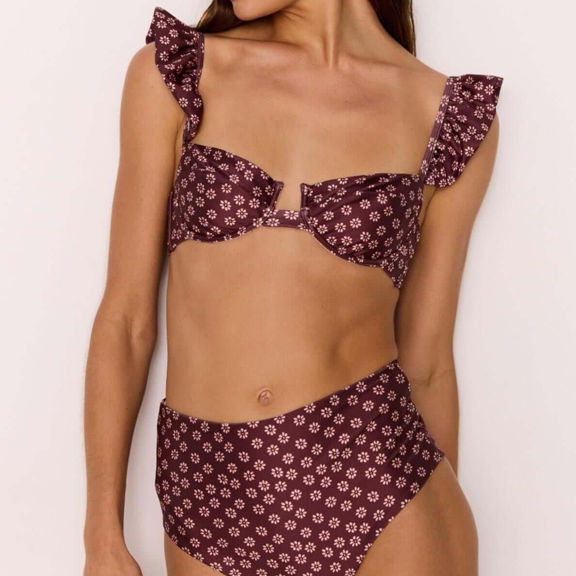 Model wearing a high-waisted bikini pant in burgundy floral print paired with a matching flounce top.