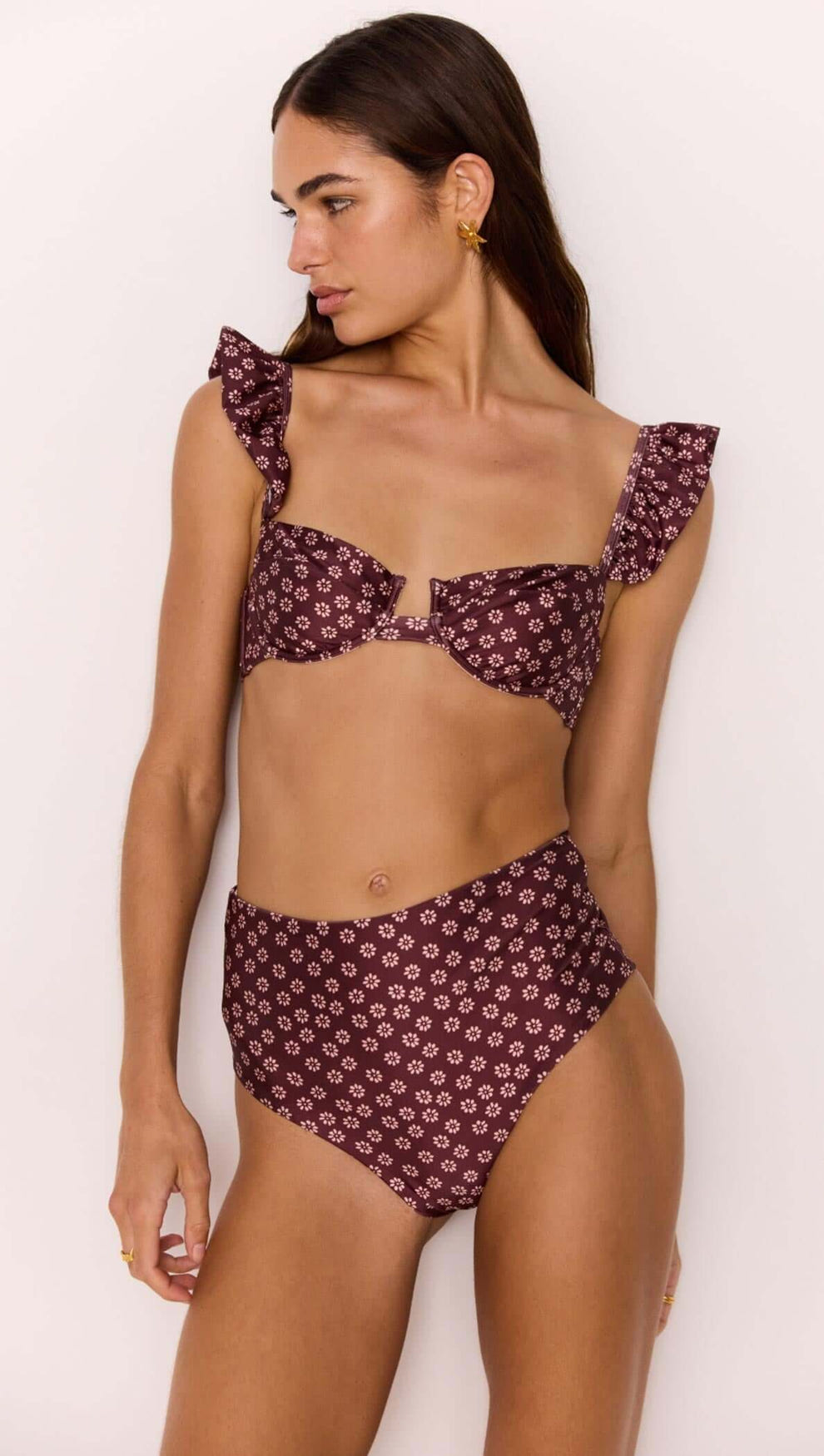 Model wearing a high-waisted bikini pant in burgundy floral print paired with a matching flounce top.