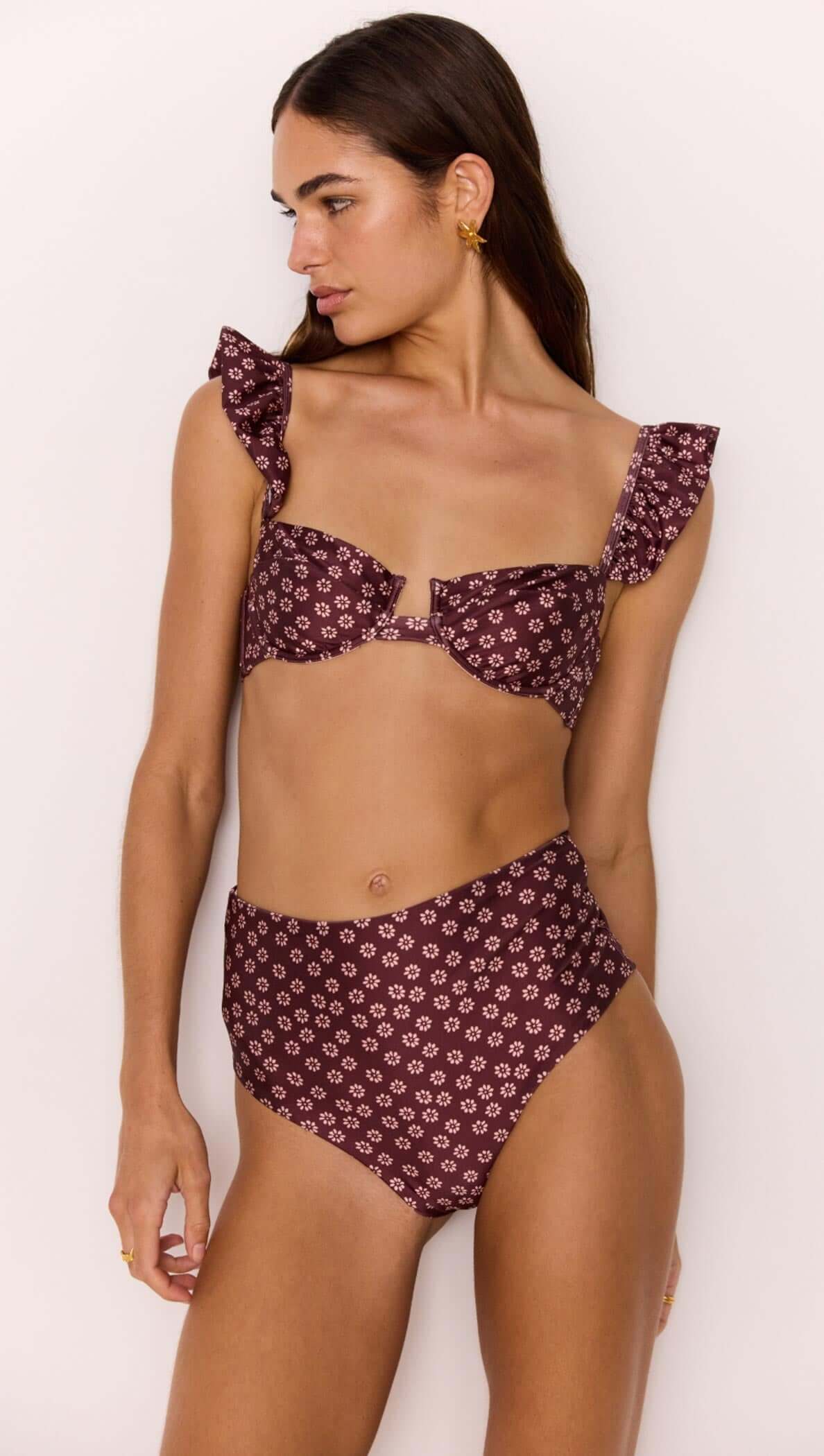 Model wearing a high-waisted bikini pant in burgundy floral print paired with a matching flounce top.