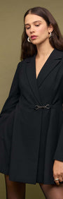 Black Blazer Mini Dress With Buckle Detail worn by a model, featuring structured shoulders and sleek design.