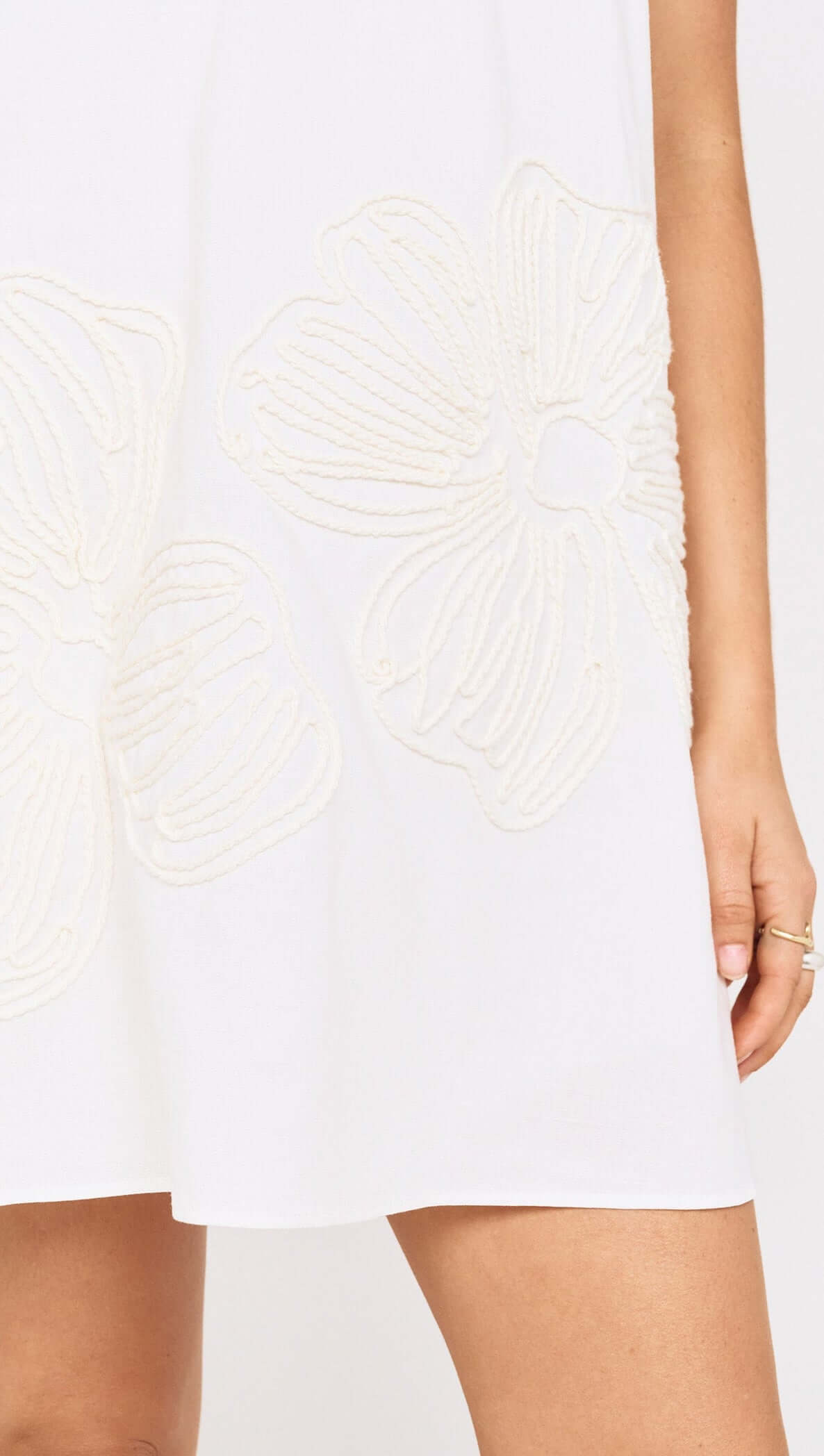 Close-up of Broderie Anglaise Cotton Mini Dress featuring beige floral embroidery on a white fabric.