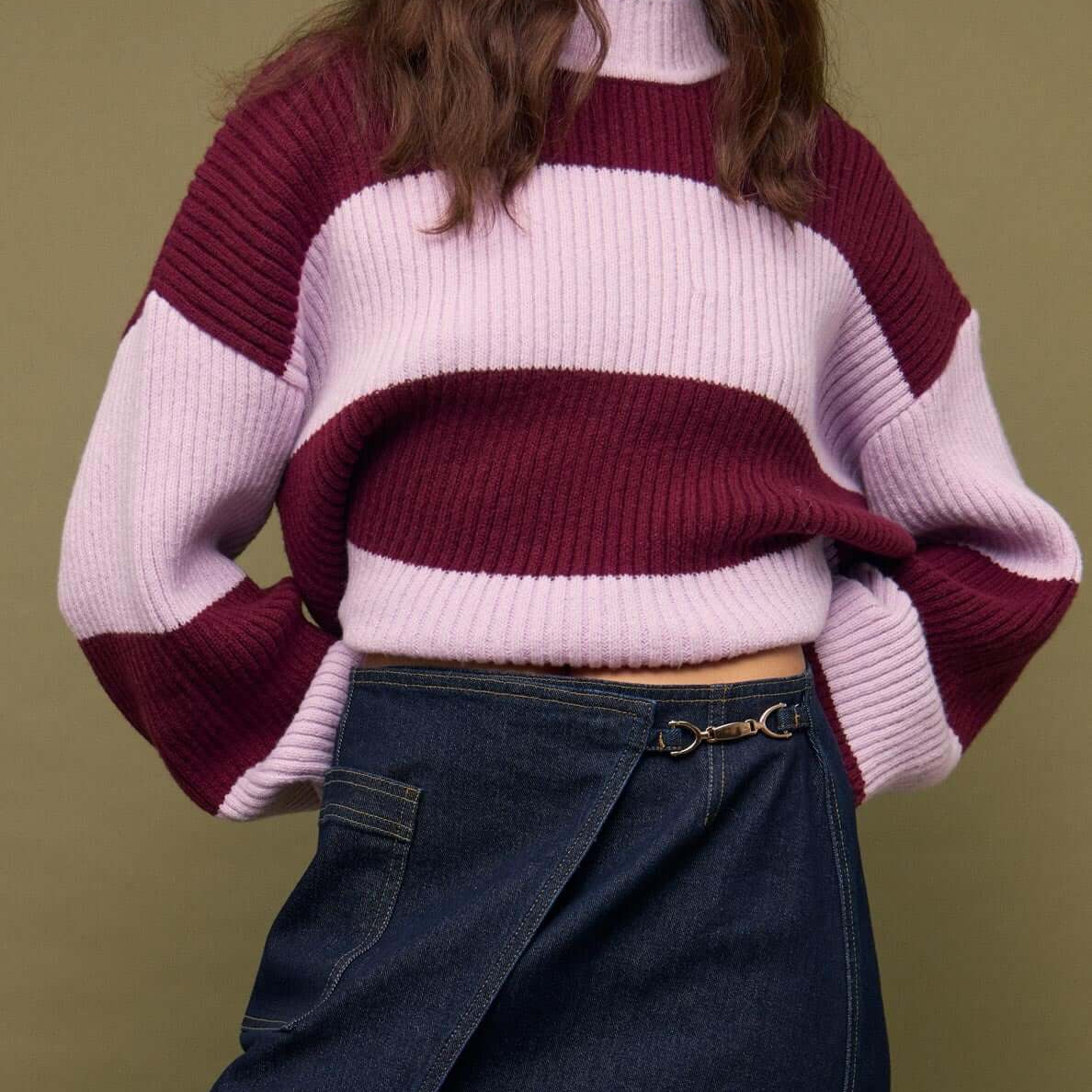 Fashionable model wearing a Denim Mini Wrap Skirt With Buckle Detail paired with a striped sweater.