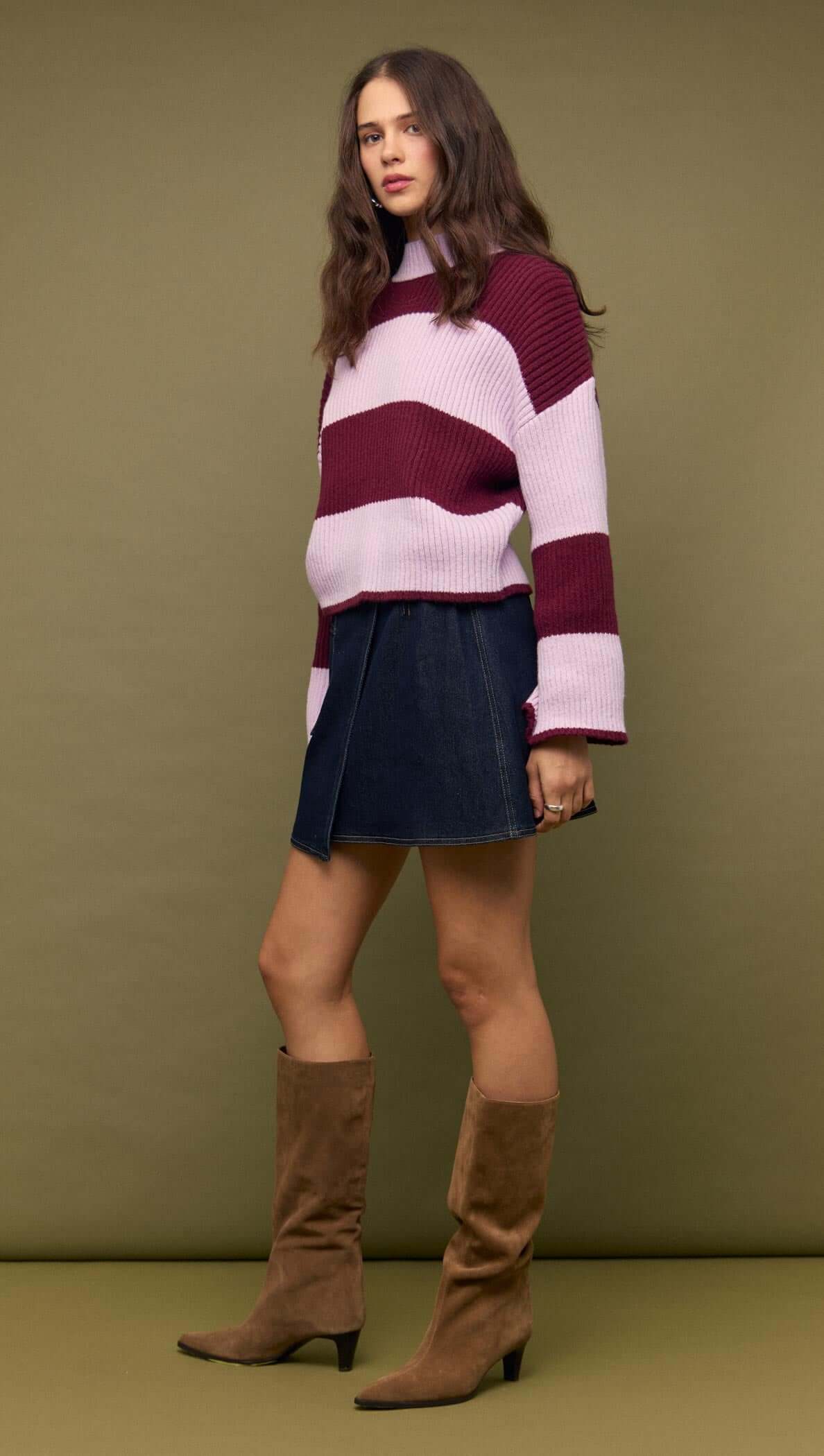 Model wearing Denim Mini Wrap Skirt With Buckle Detail and striped sweater, showcasing a stylish outfit.