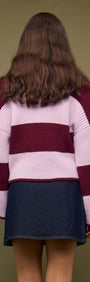 A model wearing a pink and maroon striped sweater paired with a Denim Mini Wrap Skirt With Buckle Detail, viewed from the back.