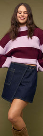 Model wearing a Denim Mini Wrap Skirt With Buckle Detail paired with a stylish striped sweater.