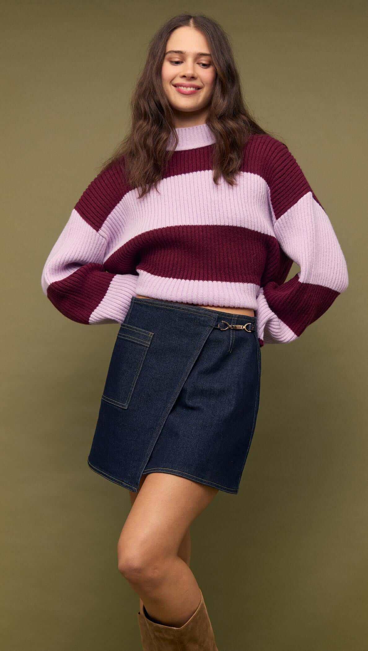 Model wearing a Denim Mini Wrap Skirt With Buckle Detail paired with a stylish striped sweater.