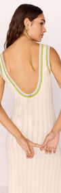Back view of a woman wearing a white knit midi dress with contrast green trim, showcasing a deep V-neckline.
