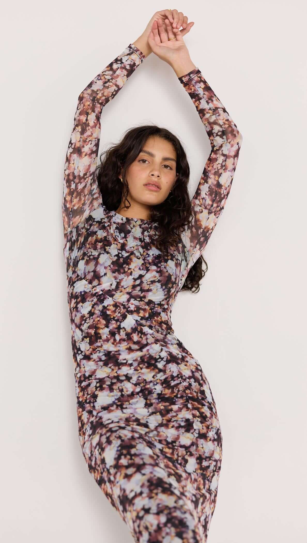 Model wearing the Audrey Mesh Midi Dress in a blurred floral print with long sleeves and a fitted silhouette.