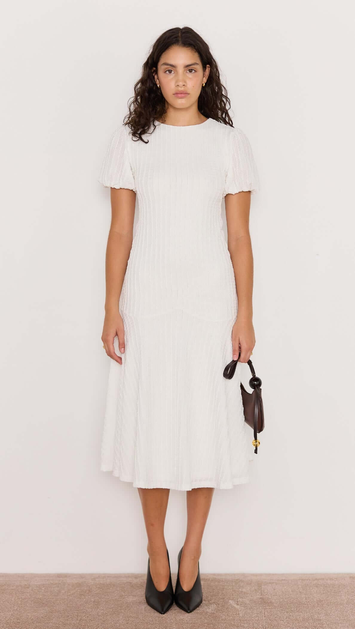 Model wearing the Anais Drop Waist Midi Dress in white, featuring puff sleeves and a drop waist silhouette.