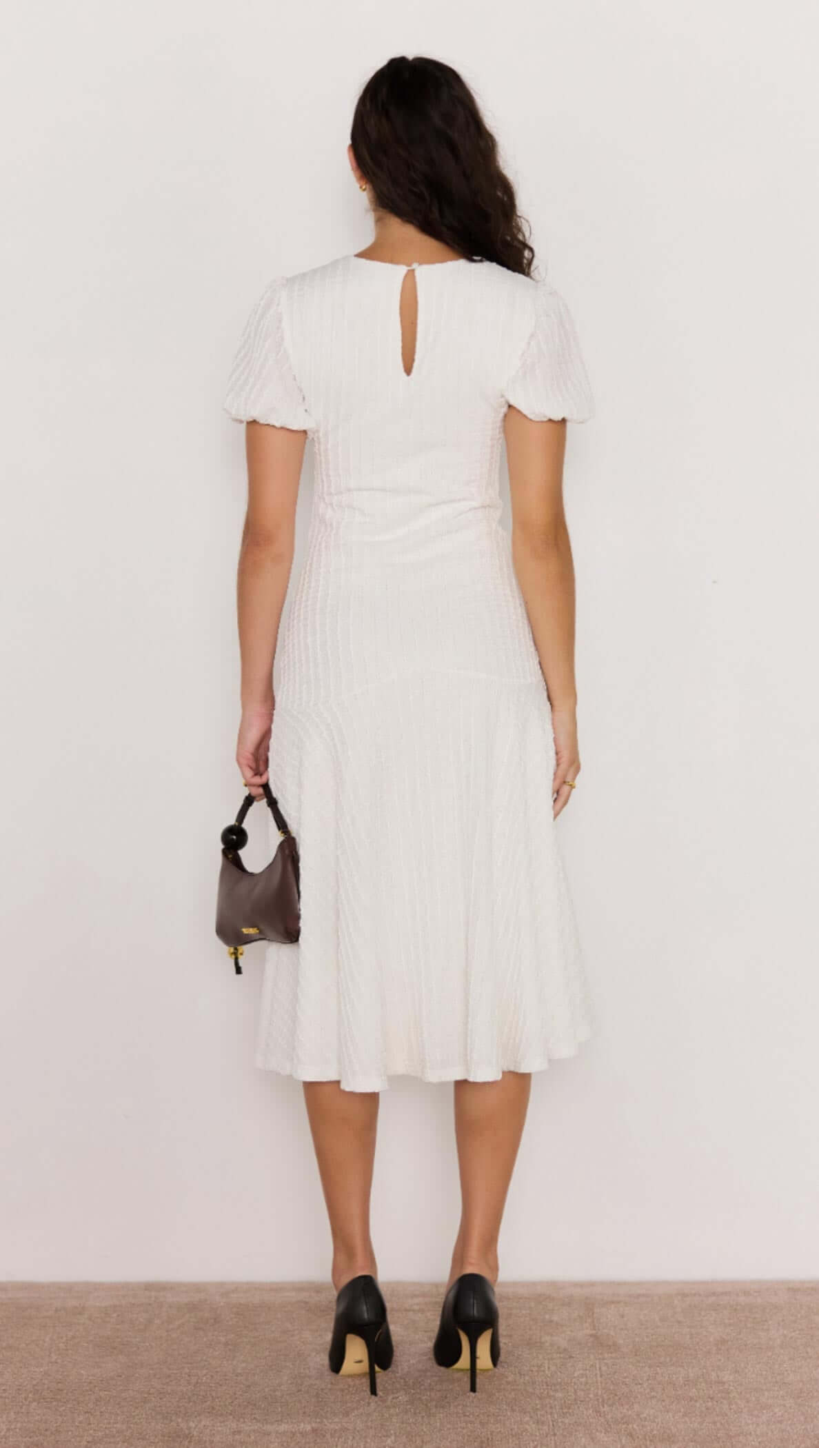 Back view of the Anais Drop Waist Midi Dress, featuring a keyhole button closure and fluttery hem in white.