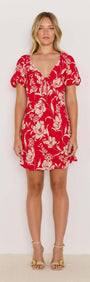 Model wearing the Poppy Mini Dress in red floral print with soft V-neckline and floaty short sleeves.