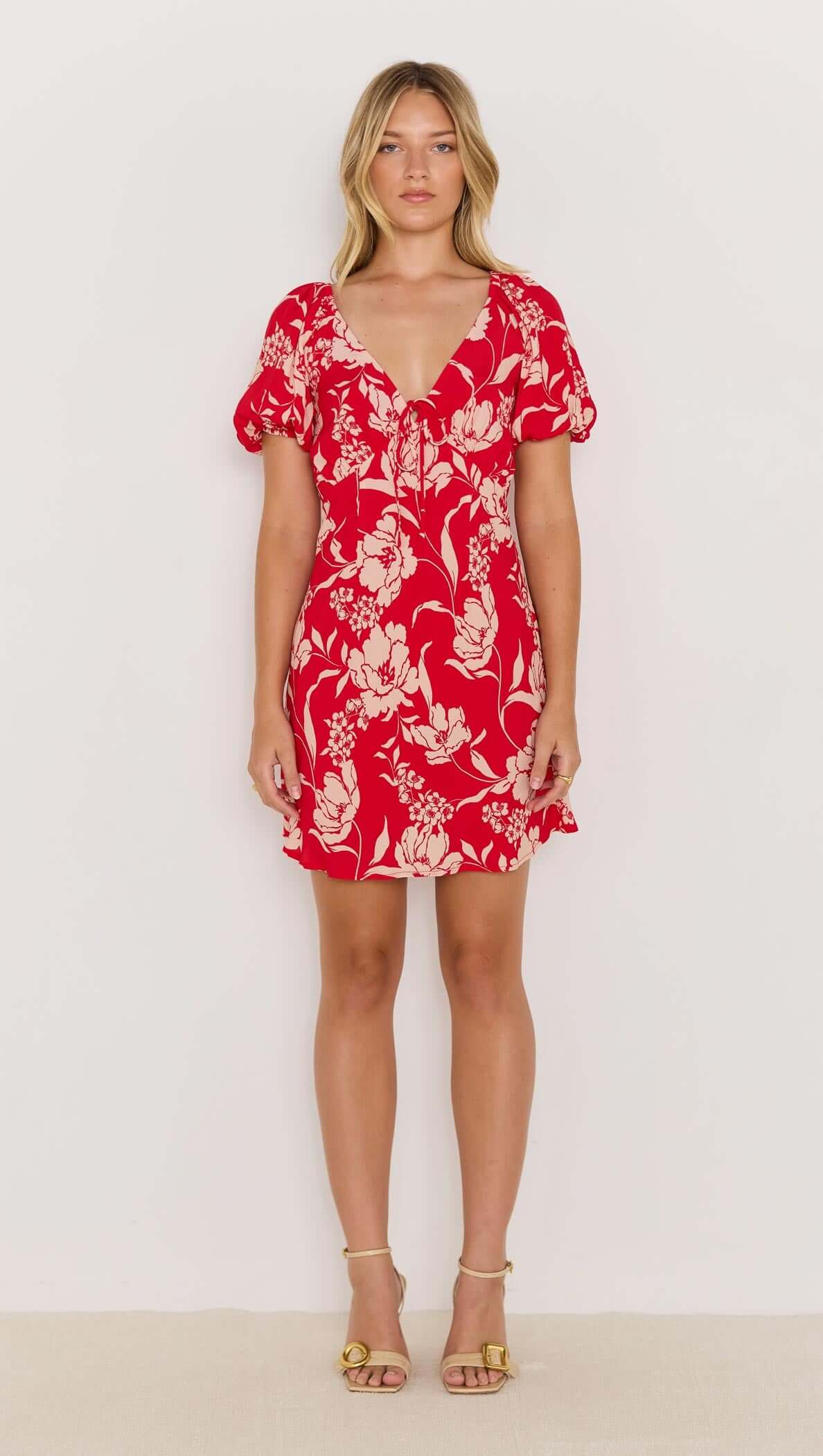 Model wearing the Poppy Mini Dress in red floral print with soft V-neckline and floaty short sleeves.
