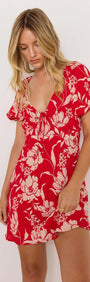 Model wearing the Poppy Mini Dress in red floral print with a soft V-neckline and floaty short sleeves.