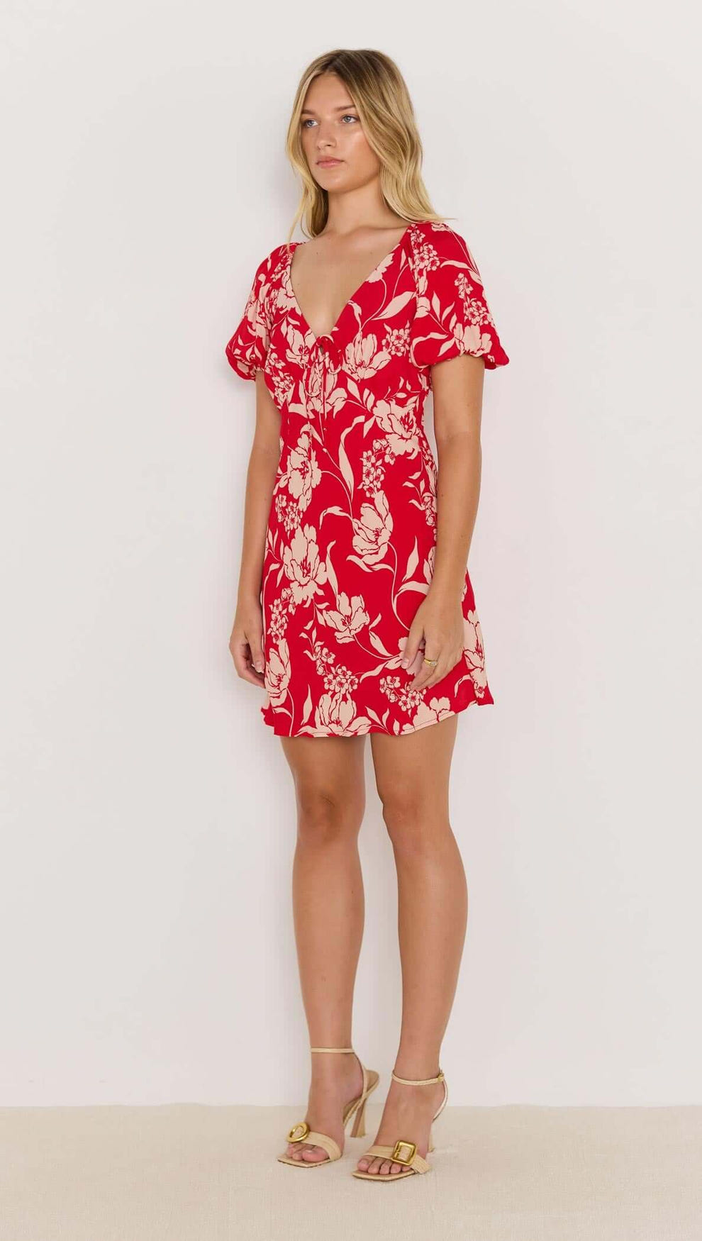 Model wearing the Poppy Mini Dress, featuring a red floral print, soft V-neckline, and floaty short sleeves.