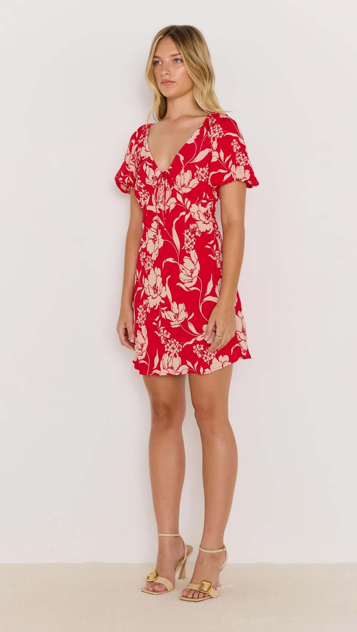 Model wearing the Poppy Mini Dress, featuring a red floral print, soft V-neckline, and floaty short sleeves.