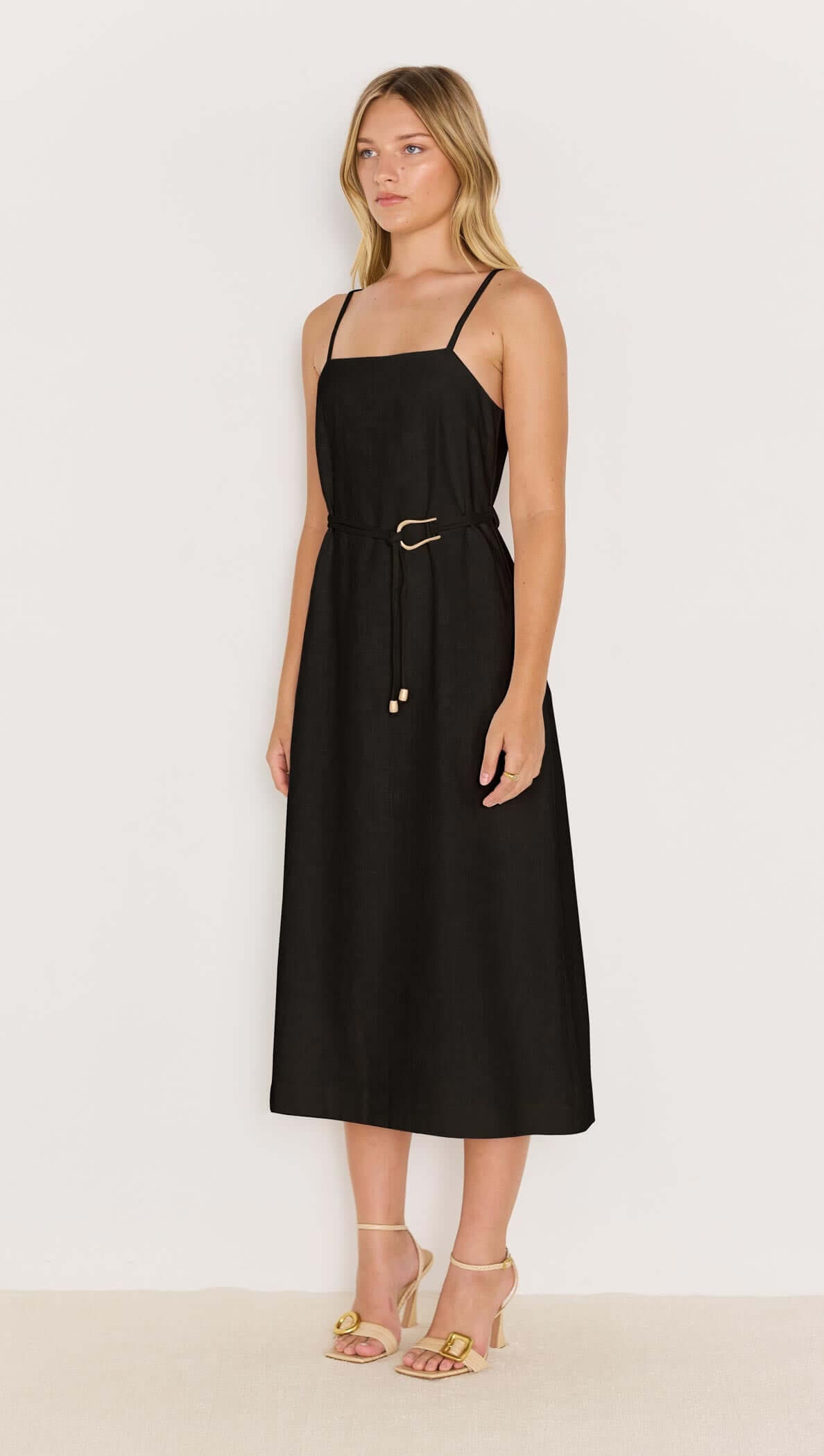Model wearing the Irena Belted Sundress in black, featuring a square neckline and gold-tone buckle belt.