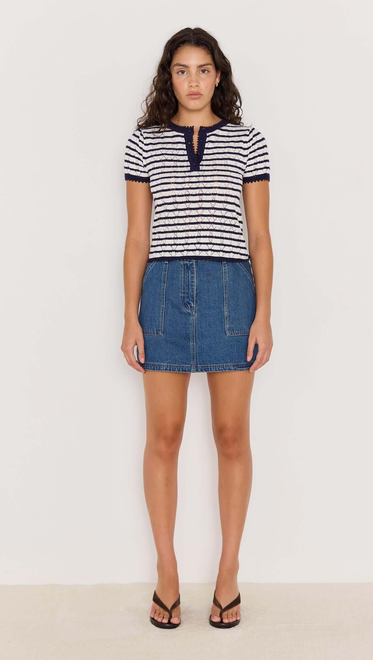 Model wearing CHLOE STRIPE KNIT TEE in navy and white stripes, paired with a denim skirt and sandals.