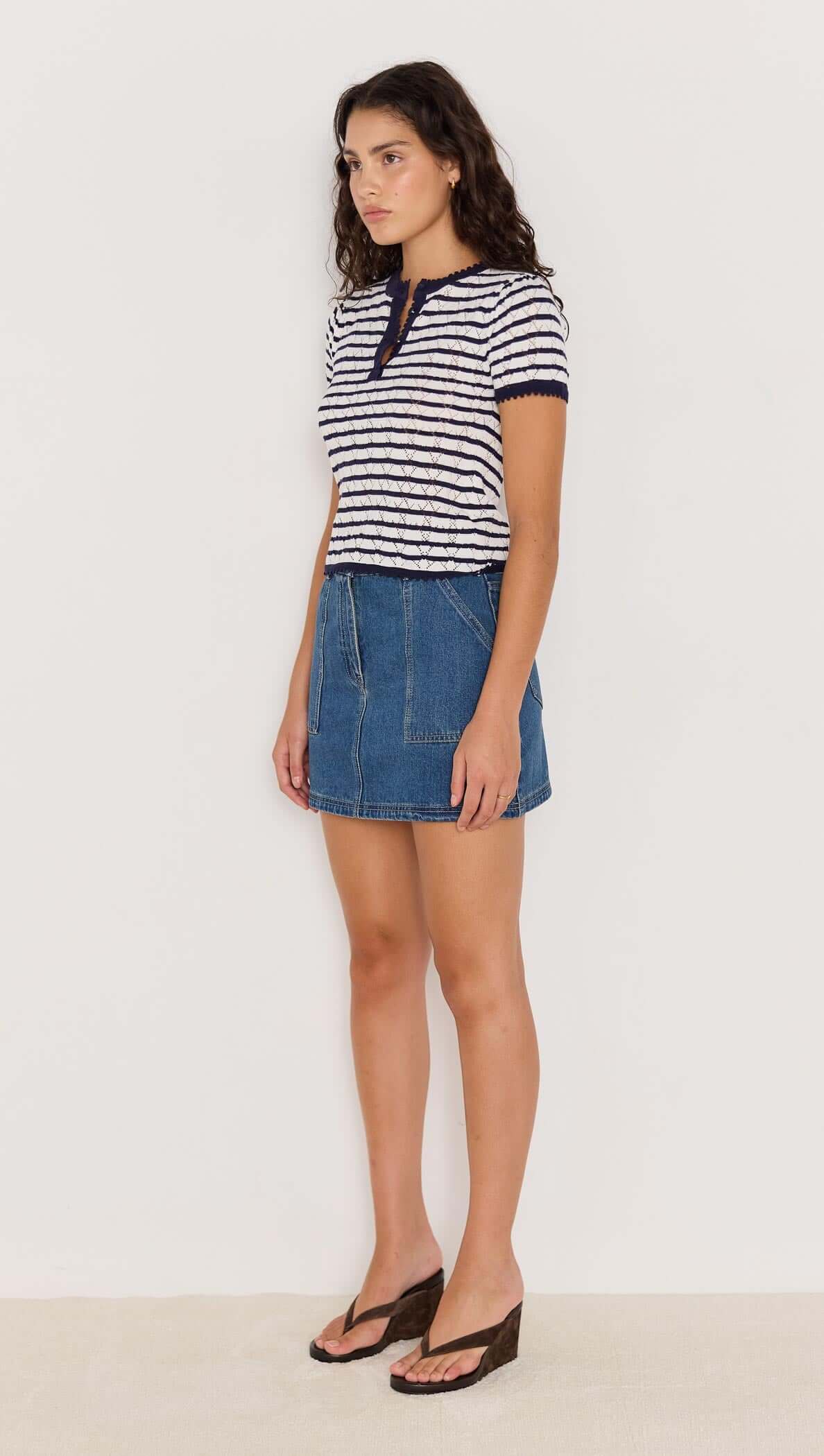 Model wearing the CHLOE STRIPE KNIT TEE, a navy and white striped tee with short sleeves, paired with a denim skirt.