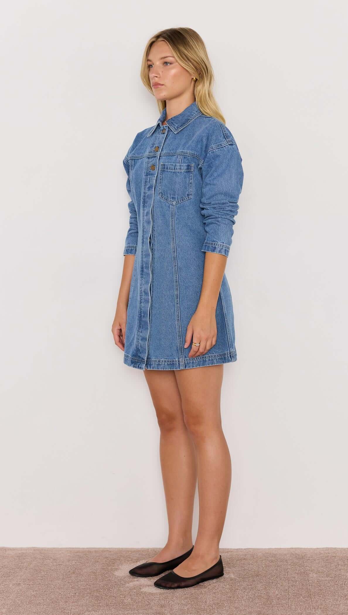 Model wearing Tully Denim Mini Dress in vintage blue, featuring long sleeves and snap button closure.