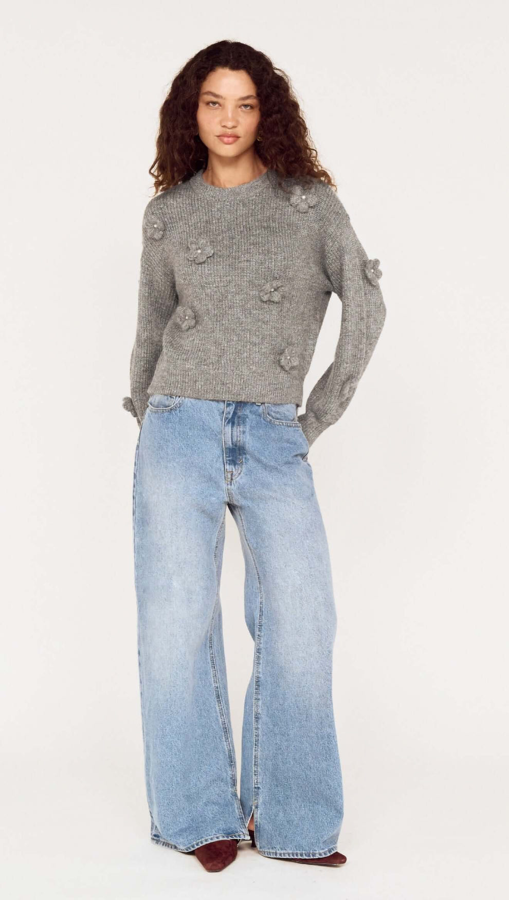 Model wearing Round Neck Grey Floral Applique Jumper with relaxed fit, paired with light blue wide-leg jeans.