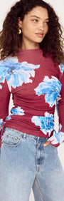 Blue floral mesh long sleeve top featuring vibrant floral pattern and fitted silhouette, styled with high-waisted jeans.