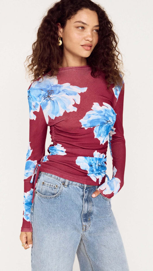 Blue floral mesh long sleeve top featuring vibrant floral pattern and fitted silhouette, styled with high-waisted jeans.