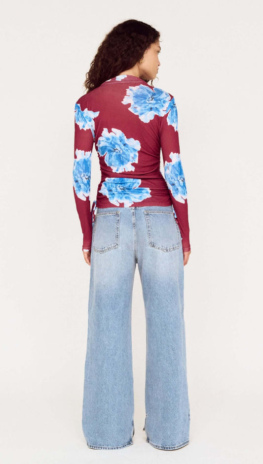 Back view of blue floral mesh long sleeve top paired with wide-leg jeans on a model.