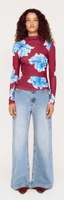 Model wearing a blue floral mesh long sleeve top with wide-leg jeans, showcasing a stylish outfit.
