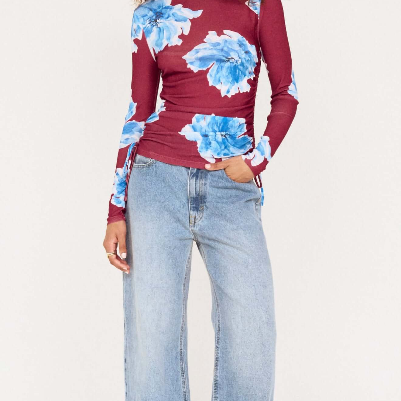 Model wearing a blue floral mesh long sleeve top paired with wide-leg jeans, showcasing a stylish and casual outfit.