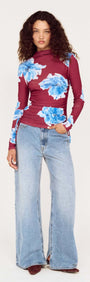 Model wearing a blue floral mesh long sleeve top paired with wide-leg jeans, showcasing a stylish and casual outfit.